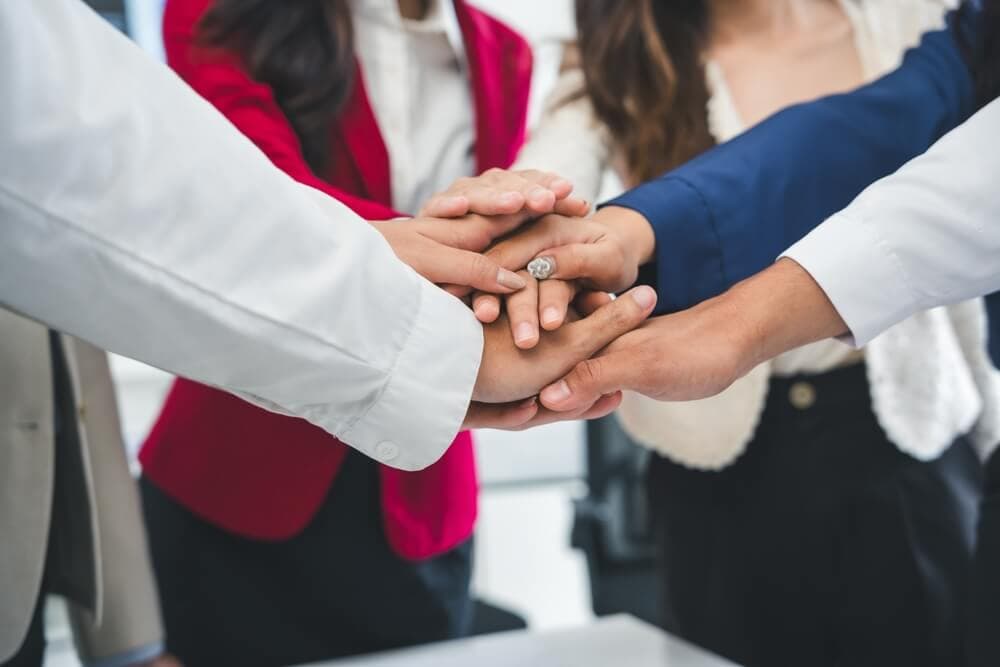 group of employees putting hands together in a circle to signify teamwork